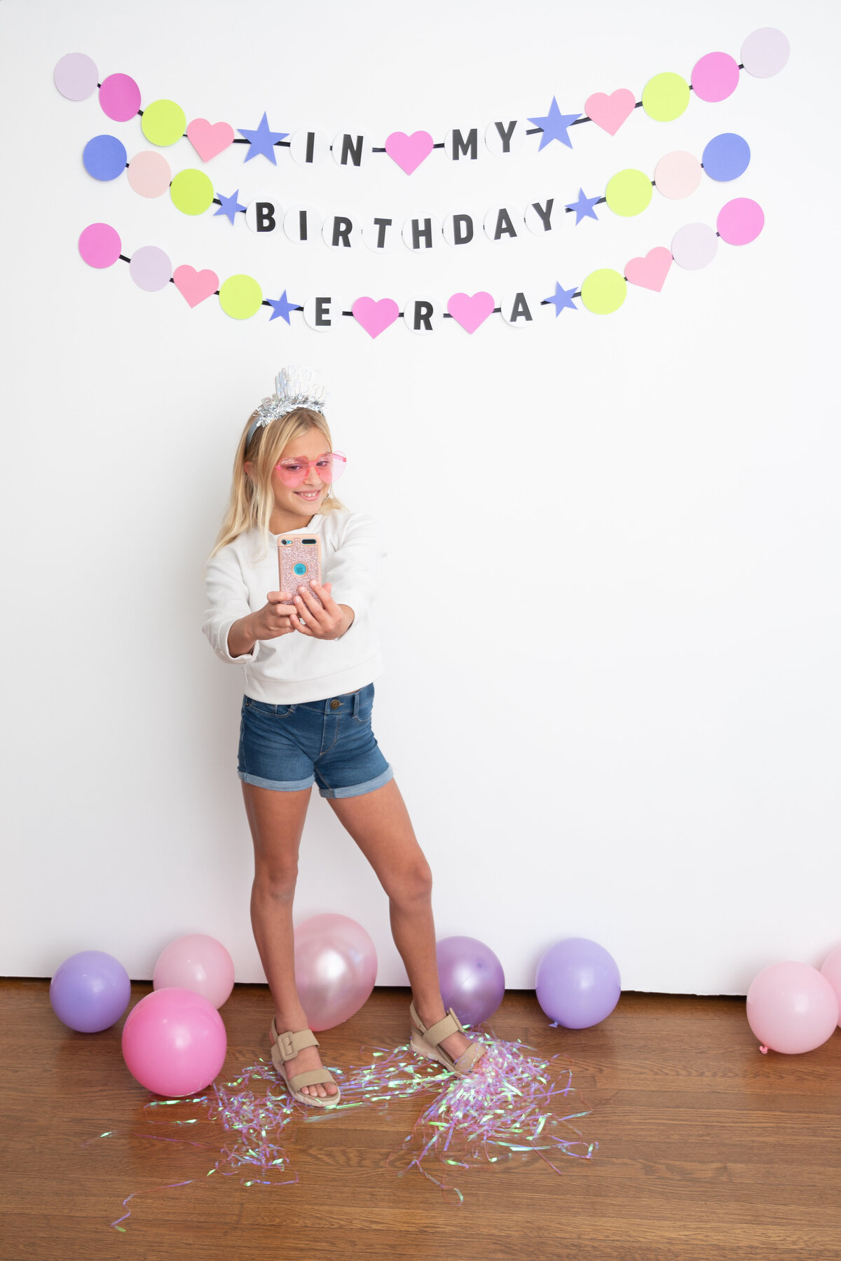 birthday girl in tiara, holding phone taking a selfie