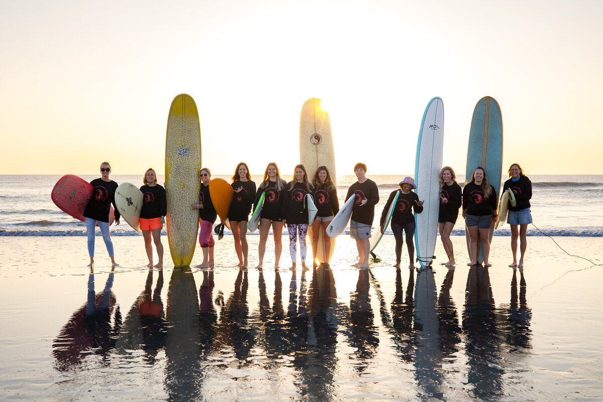 Surf Team poses at sunrise with surfboards