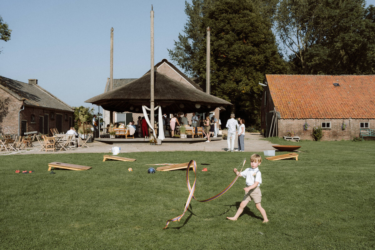 Sfeervolle bruiloft bij Nigtevecht Freeland Farm, met een persoonlijk aangekleed decor en het bruidspaar dat geniet van een lange borrel in een gezellige, intieme sfeer. Zoontje loopt met een sliert door de tuin. 