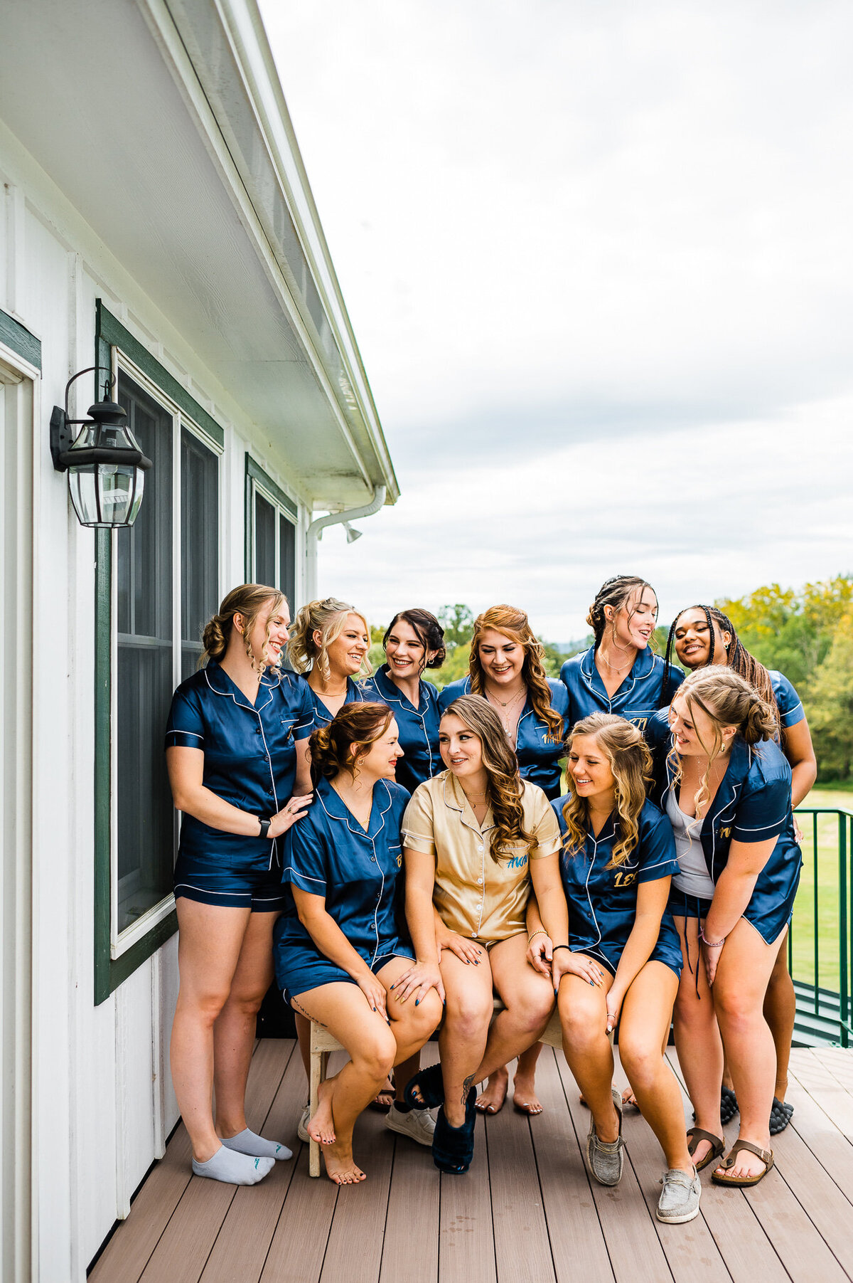 bride sitting in the middle of her bridesmaids who are in matching silk pajamas on a balcony at Shenandoah wedding venue