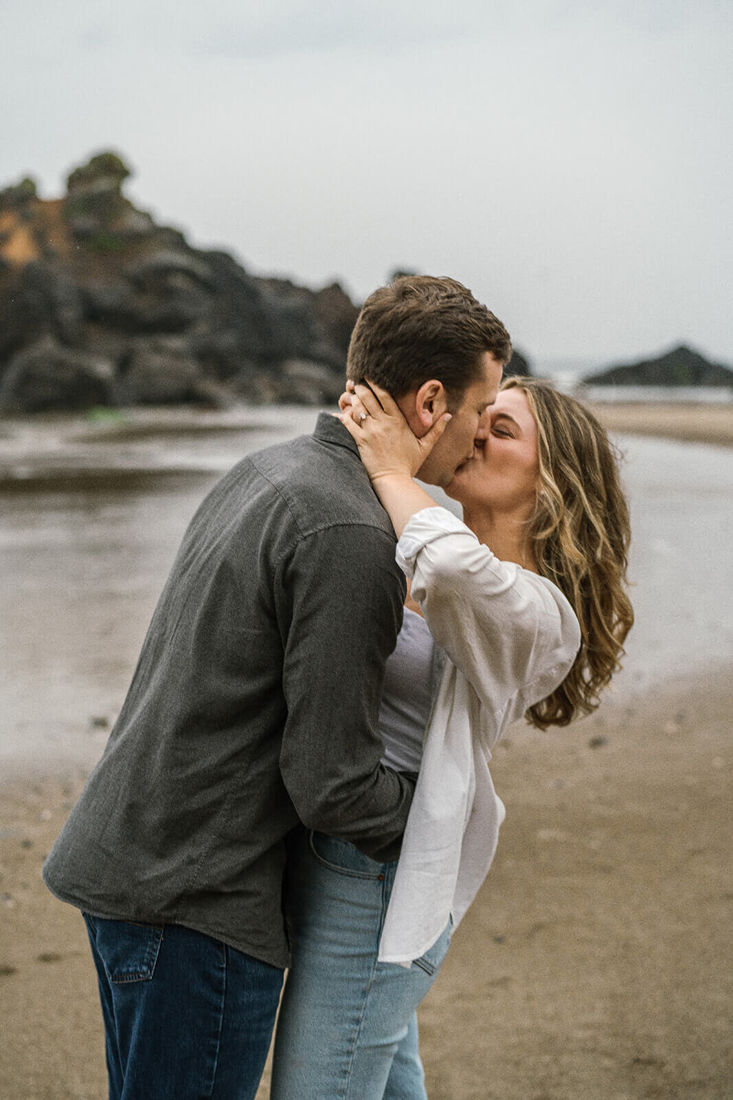 A couple kissing in the misty rain at the beach. 