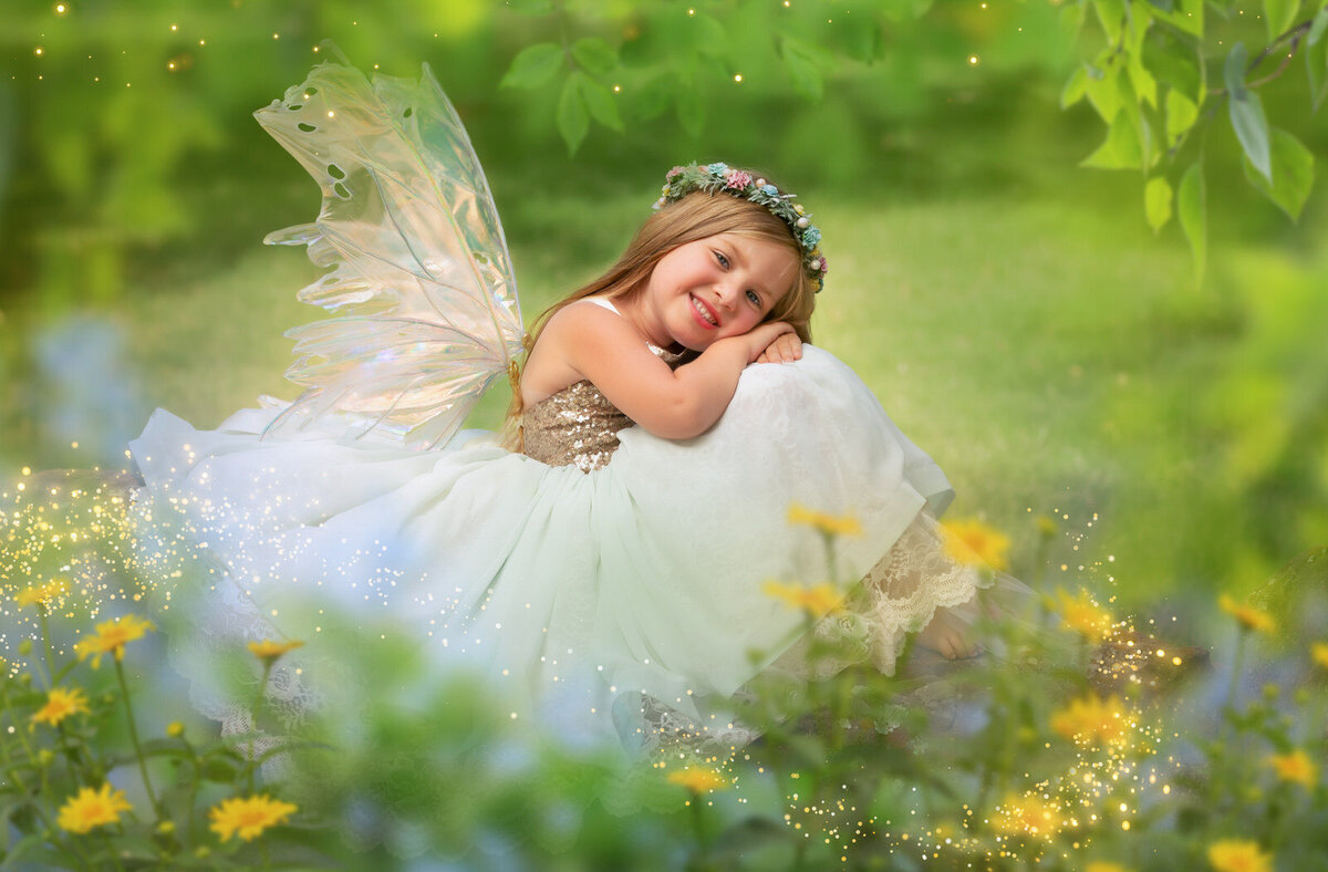 girl-in-blue-couture-gown-with-sparkles-on-botice-and-fairy-wings-in-garden-with-yellow-flowers-arlington-tx