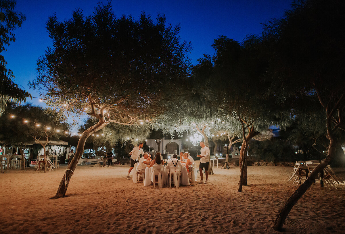 A group of guests relax under the stars at a beach reception