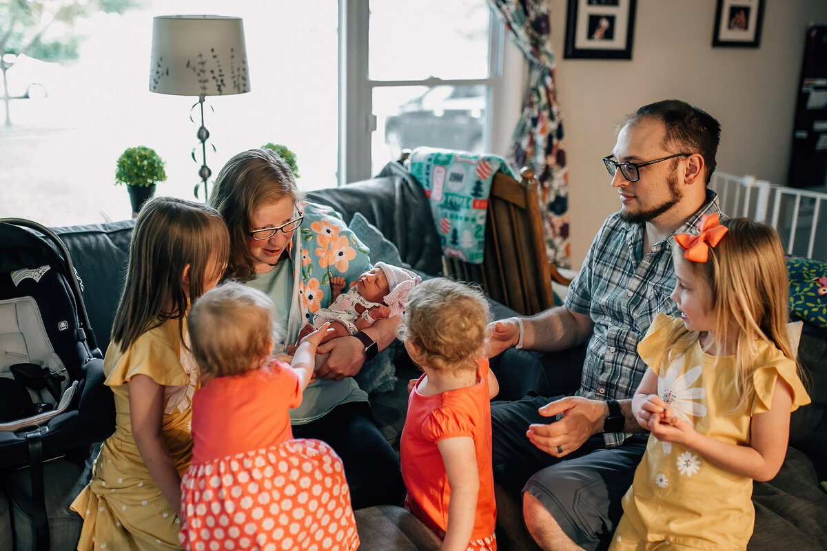 Lifestyle photographer capturing a family hanging out in living room with newborn baby.