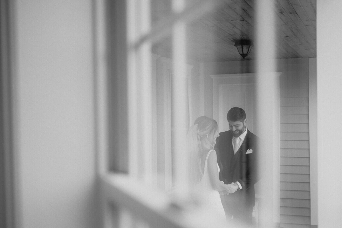 Shot through a window looking at bride and groom before wedding ceremony