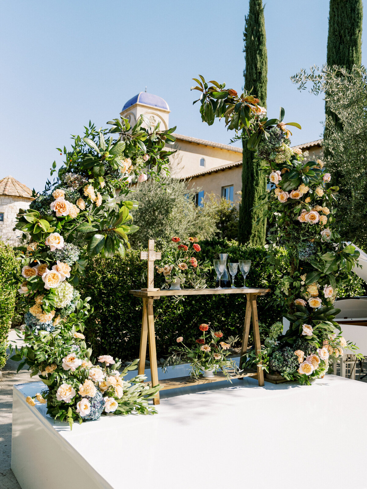 Lush floral ceremony arch at Allegretto Vineyard—elegant greenery, pastel blooms, and Tuscan charm under the California sun.