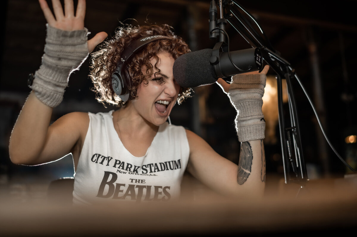 BYOBrand Podcast Host - Hannah Ellaham Arms Up Screaming Into Microphone wearing Beatles shirt - Image by Ahnvee Photography