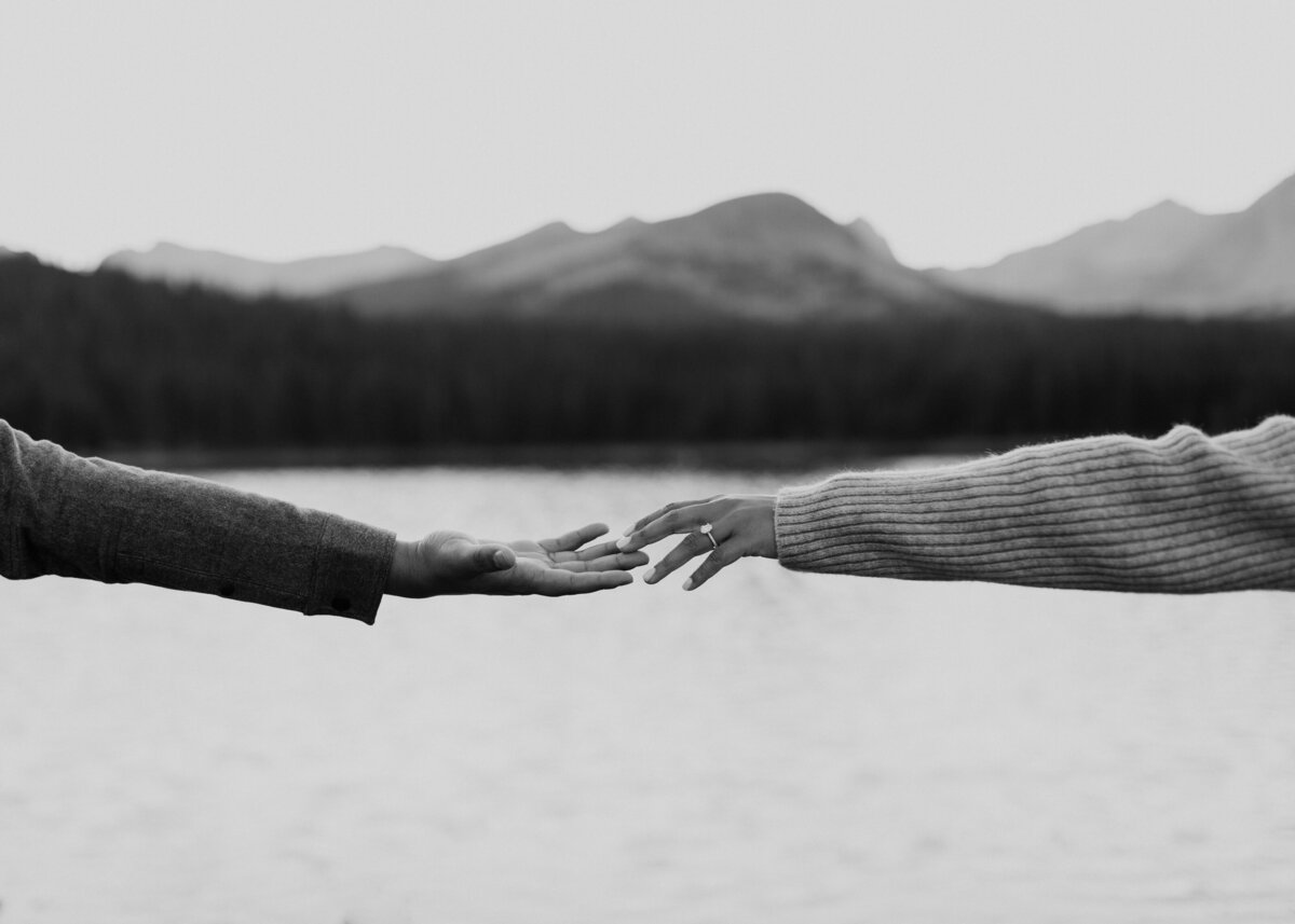 Engaged couple holding hands with mountains in the background in CO