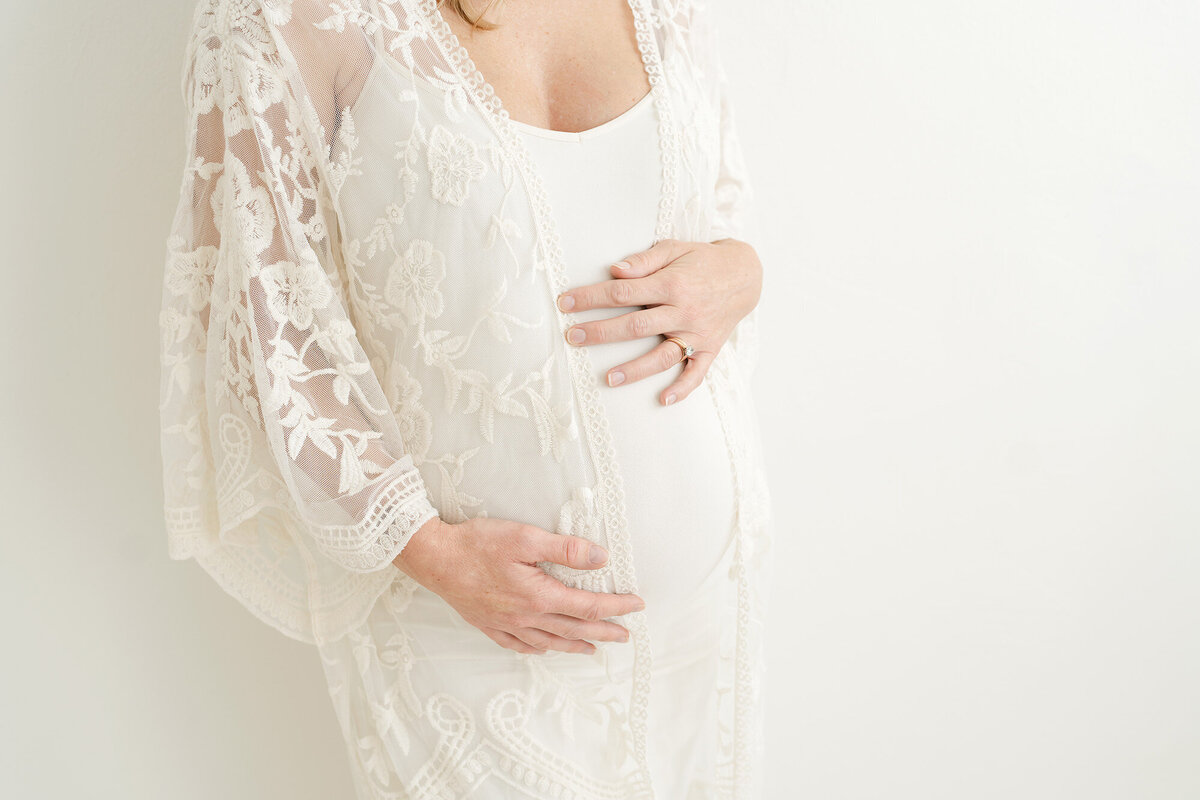 Focus on pregnant belly with hands for Louisville maternity session