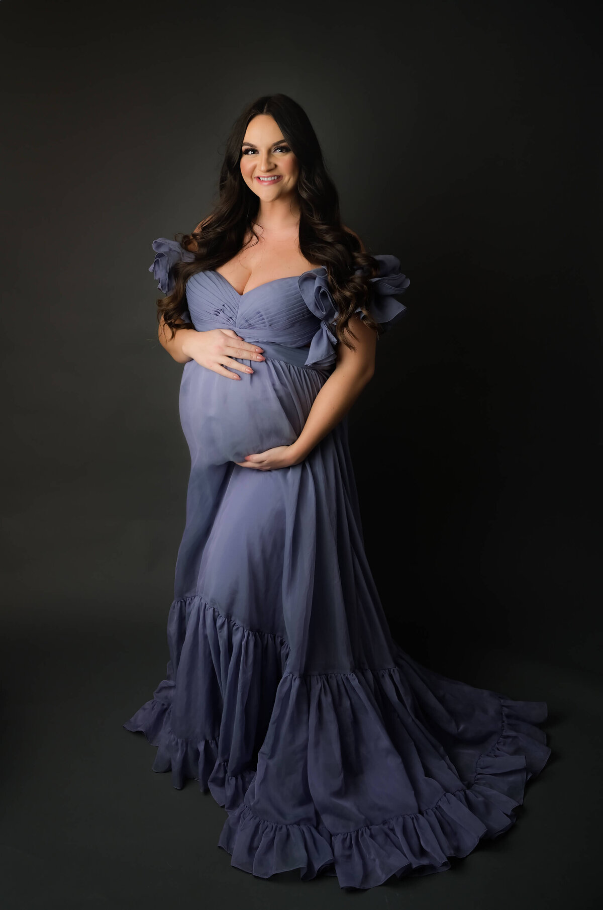 E. Benecki Photography captures this elegant expecting mother on a dark background. Mom is wearing a long flowing purple dress.