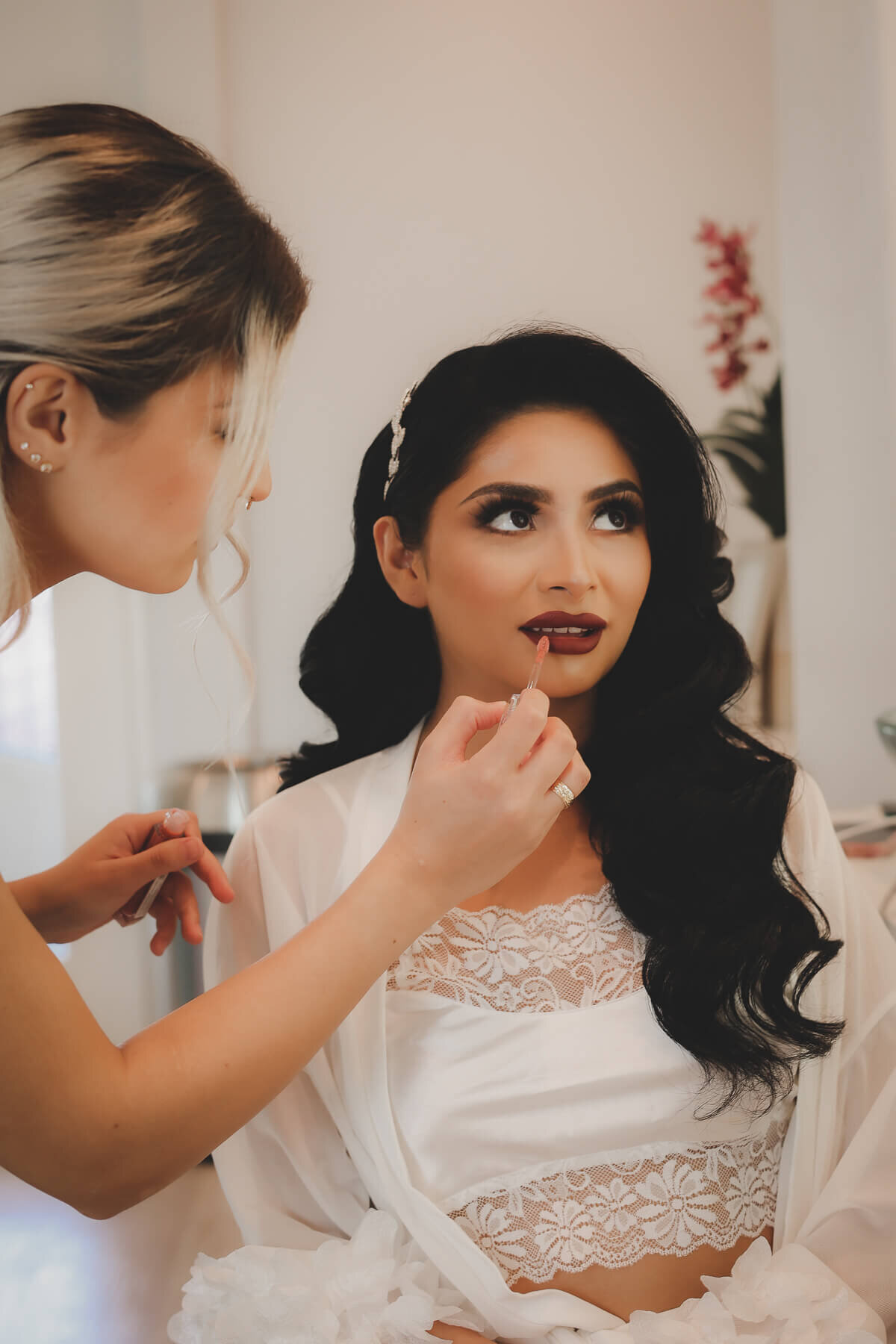 A bride has lipstick applied as she prepares for her wedding day.