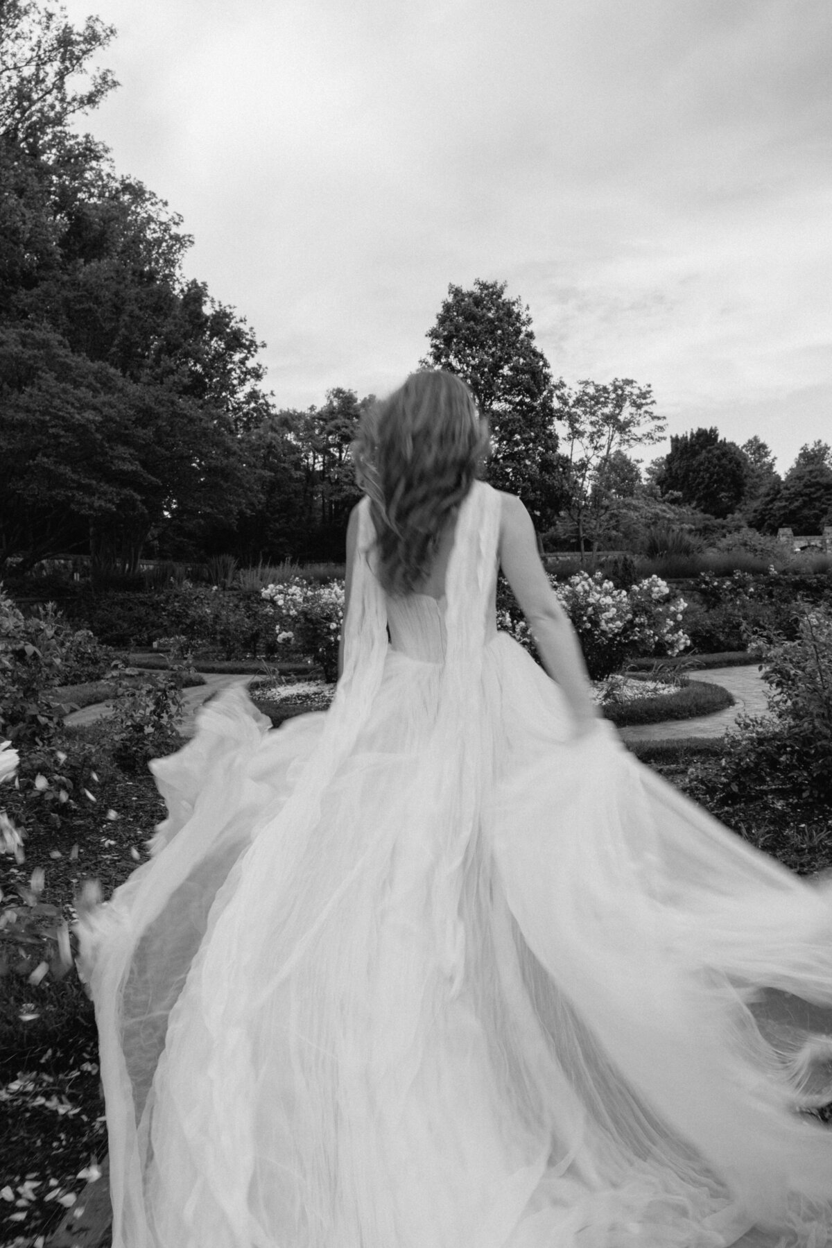 Bride in Anthropologie Watters wedding dress strolling through the lush gardens of the Biltmore Estate.