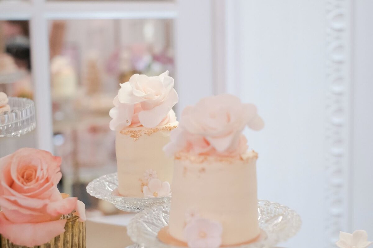 mini cakes on glass plates with large sugar roses
