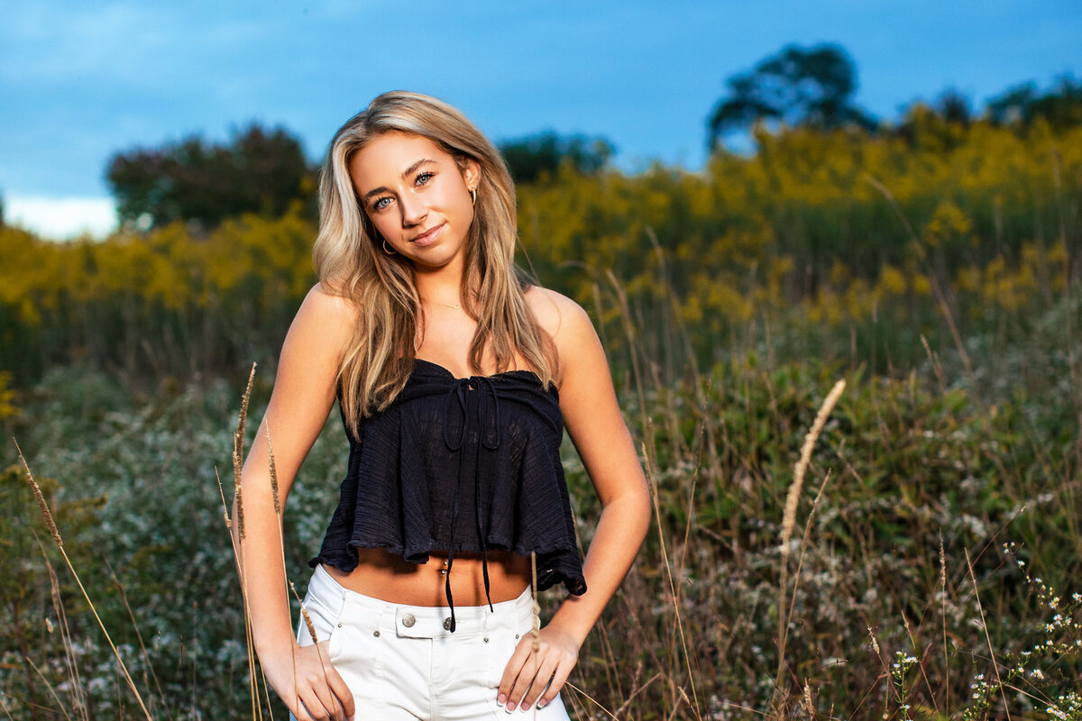A beautiful blonde haired tanned girl stands in a field thinking about what's next for her during her senior season