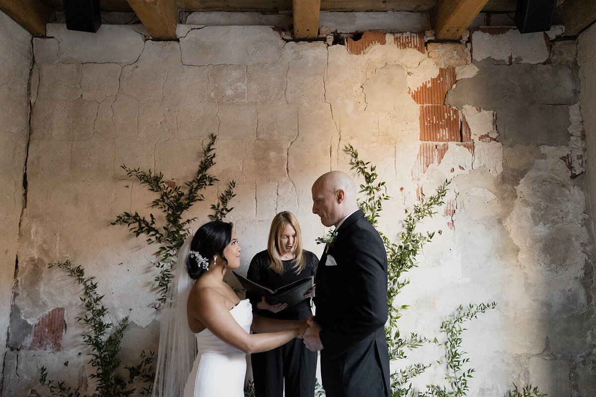 couple holds hands as the officiant blesses the rings