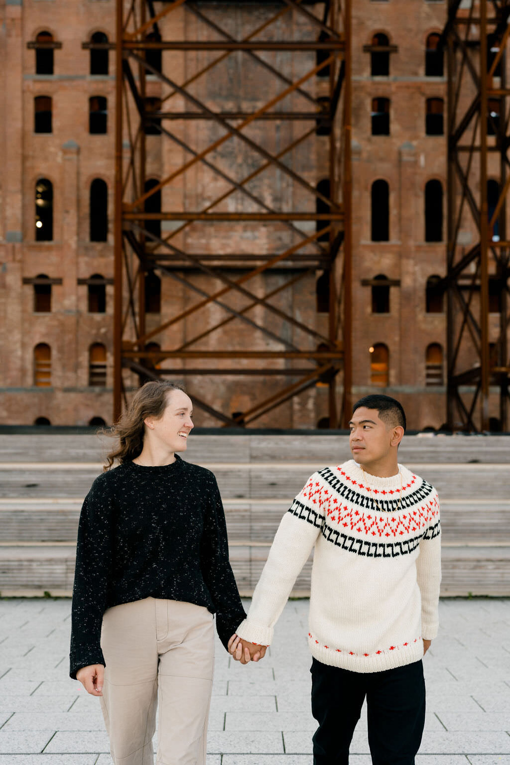 couple holding hands and walking in a  plaza