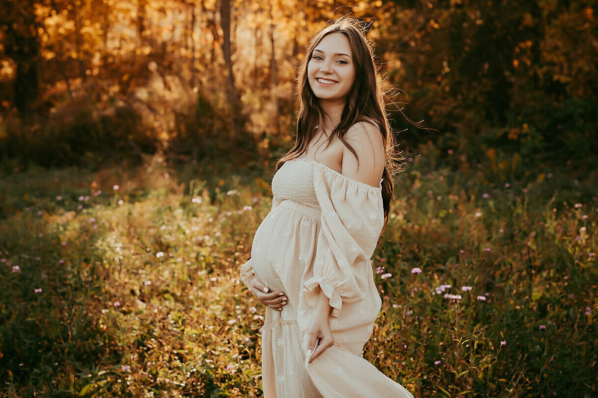 A pregnant woman dancing in a field during golden hour in Canandaigua, NY