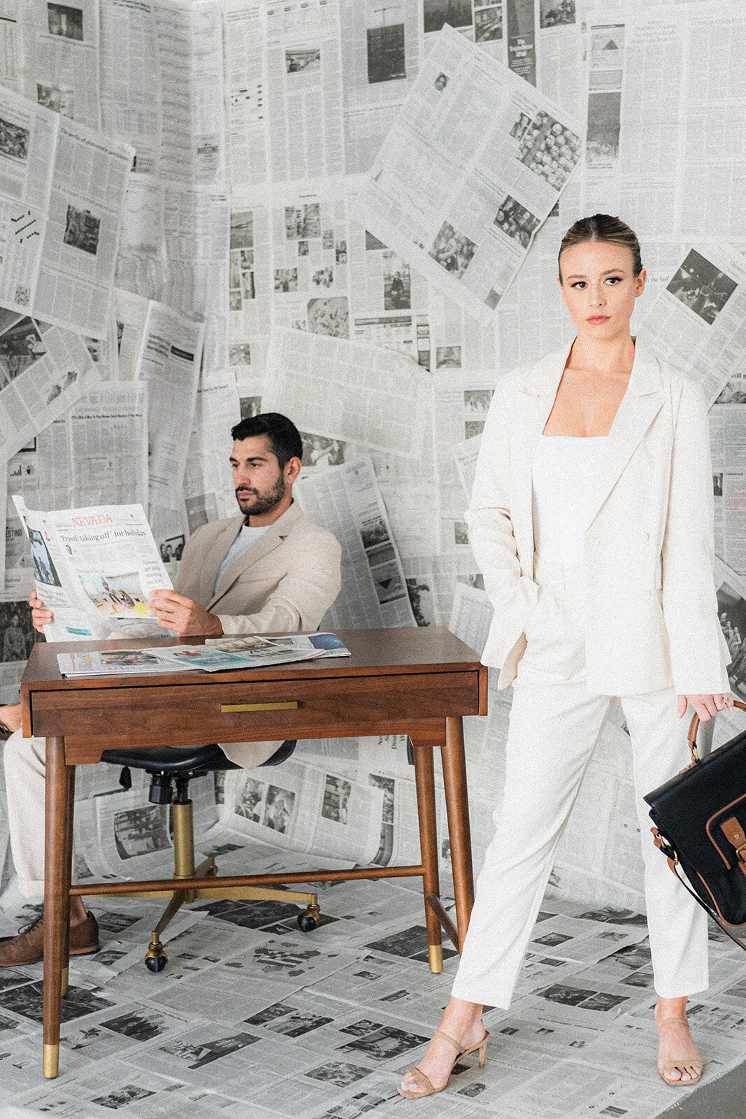 A couple is at a desk with a newspaper background
