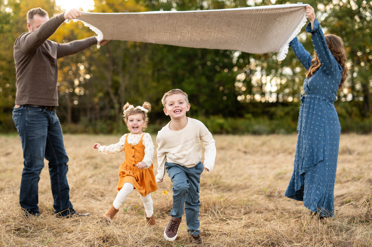 Young children running under a blanket