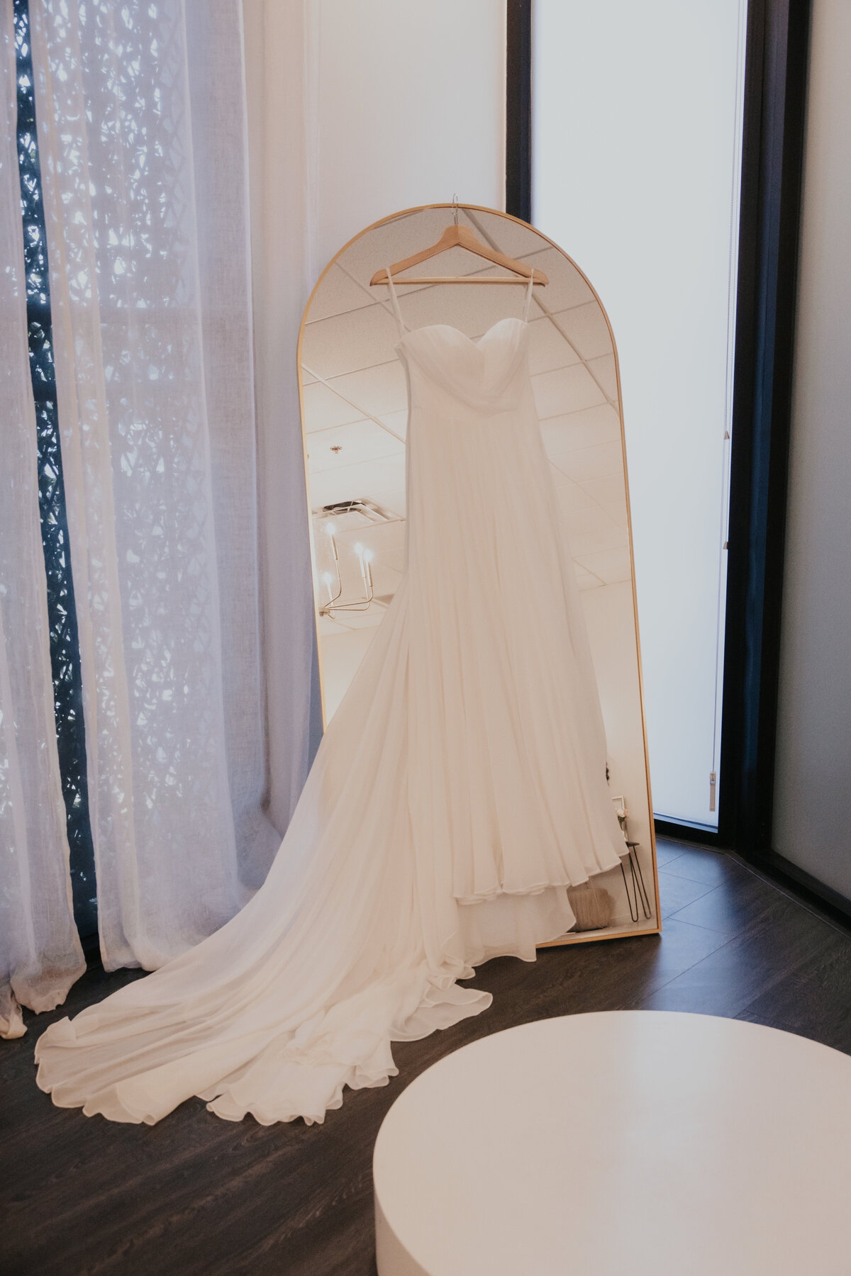 Brides wedding gown hanging up on a mirror in the bridal suite of the croft wedding venue