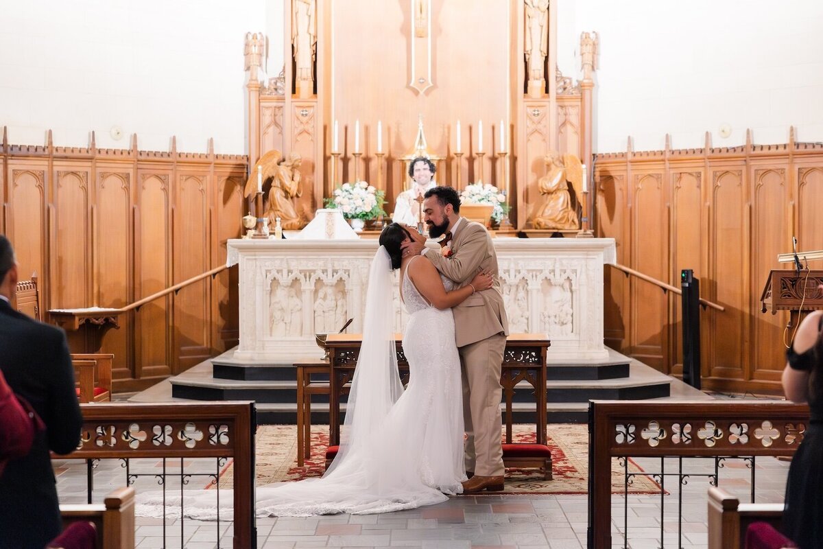 Bride and groom kissing after exchanging vows at altar