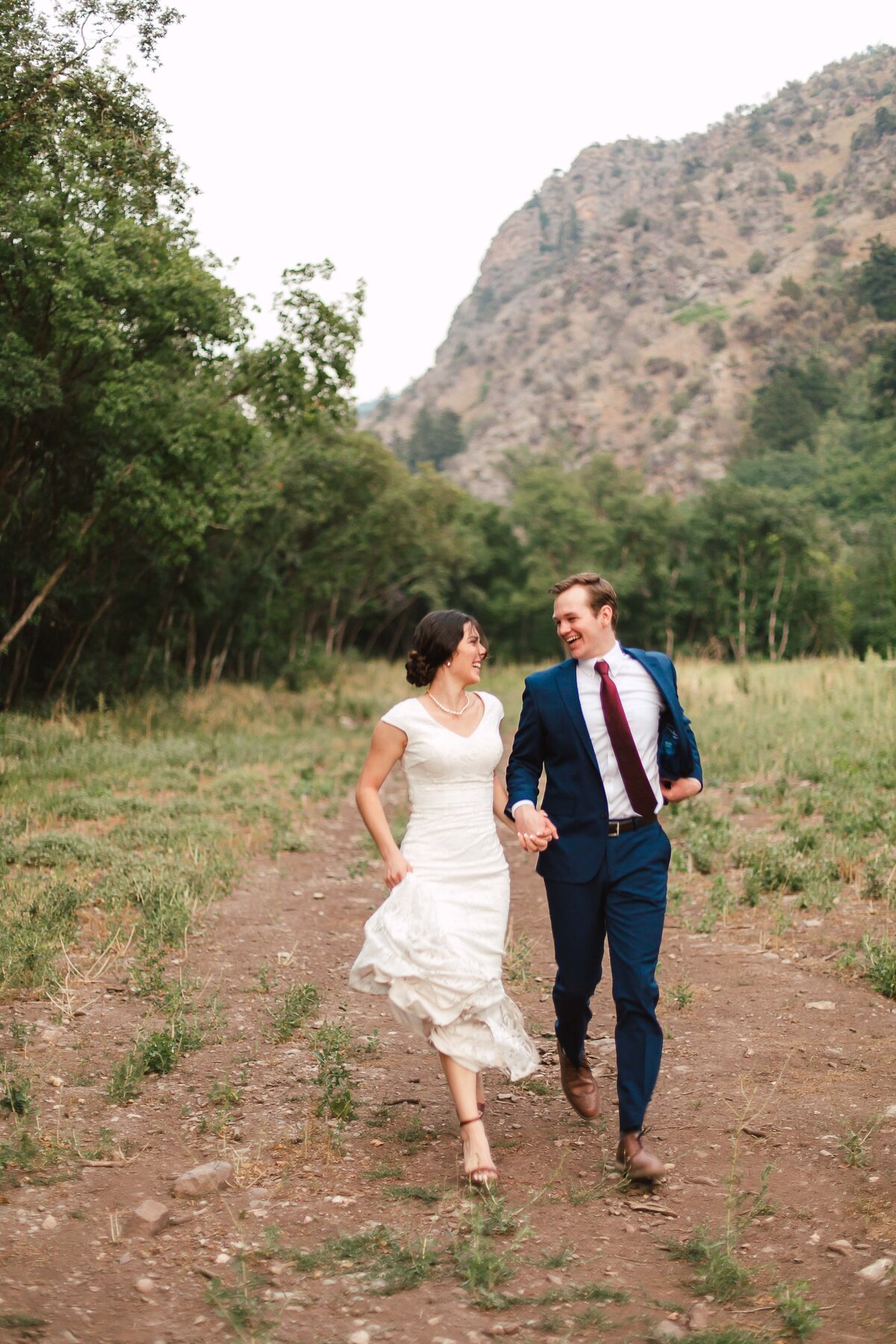 Bride and groom running together in photo at Cherry Peak Ski Resort in Utah by Utah Wedding Photographer