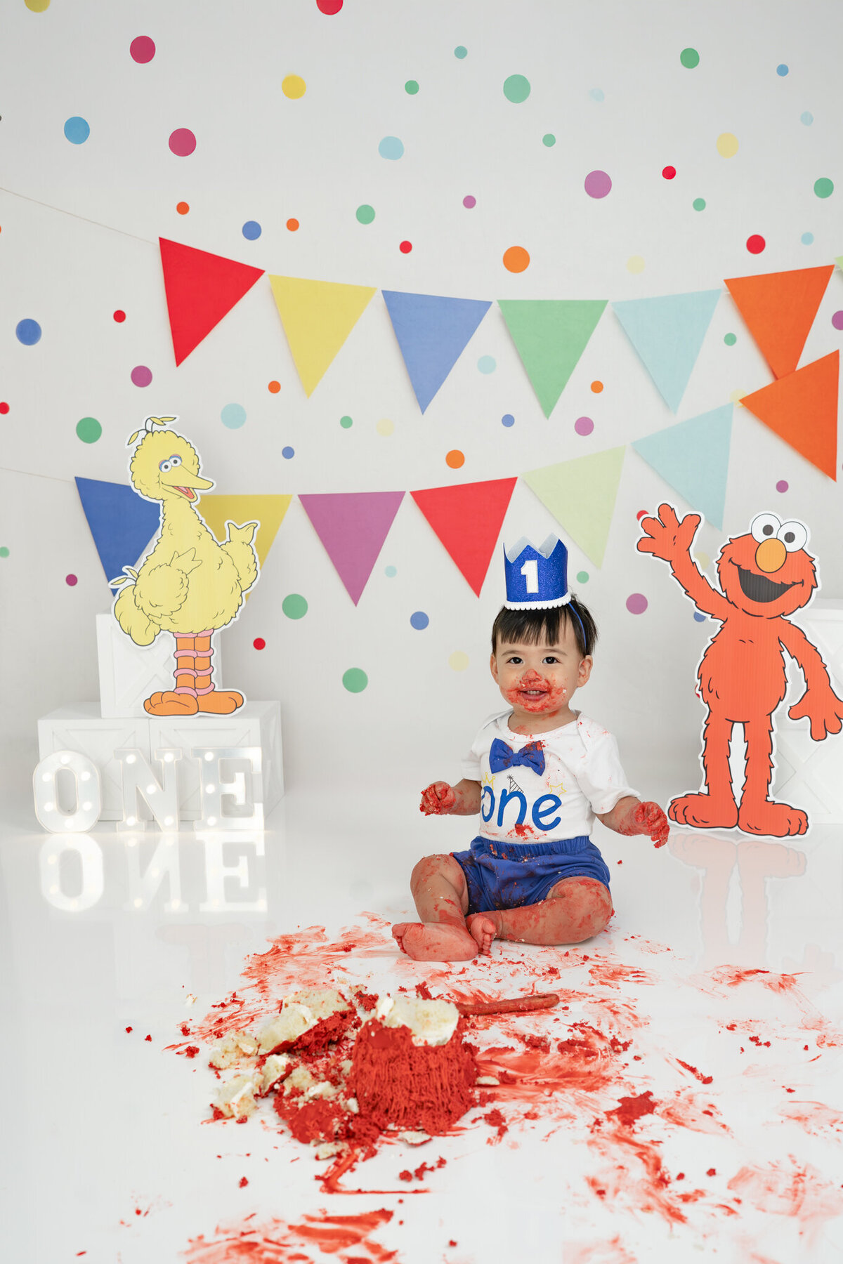 Boy in birthday outfit eating an Elmo cake during themed cake smash session— captured by Alliston and Barrie cake smash photographer.
