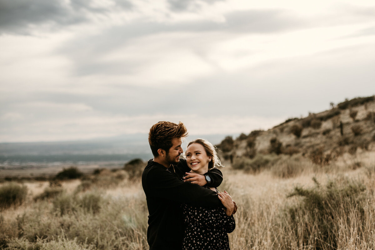 engaged couple holding each other in desert