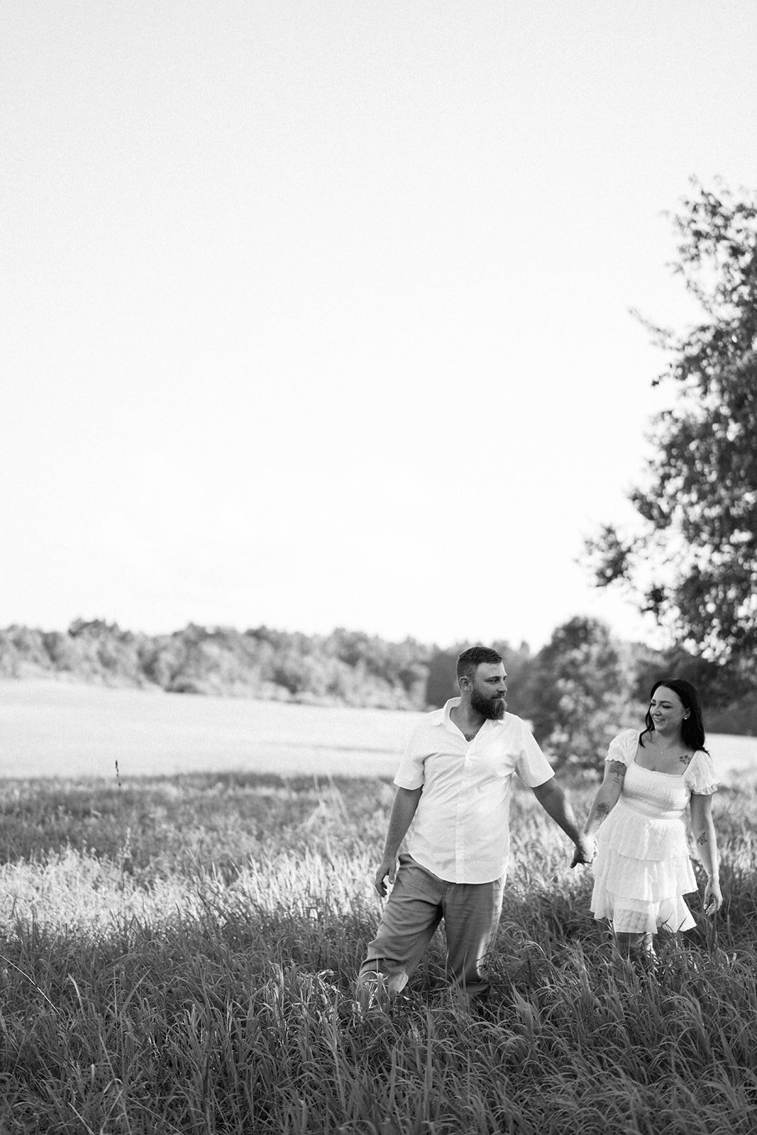 Kali and Joe walking through a grassy field at sunset on private property outside Detroit.