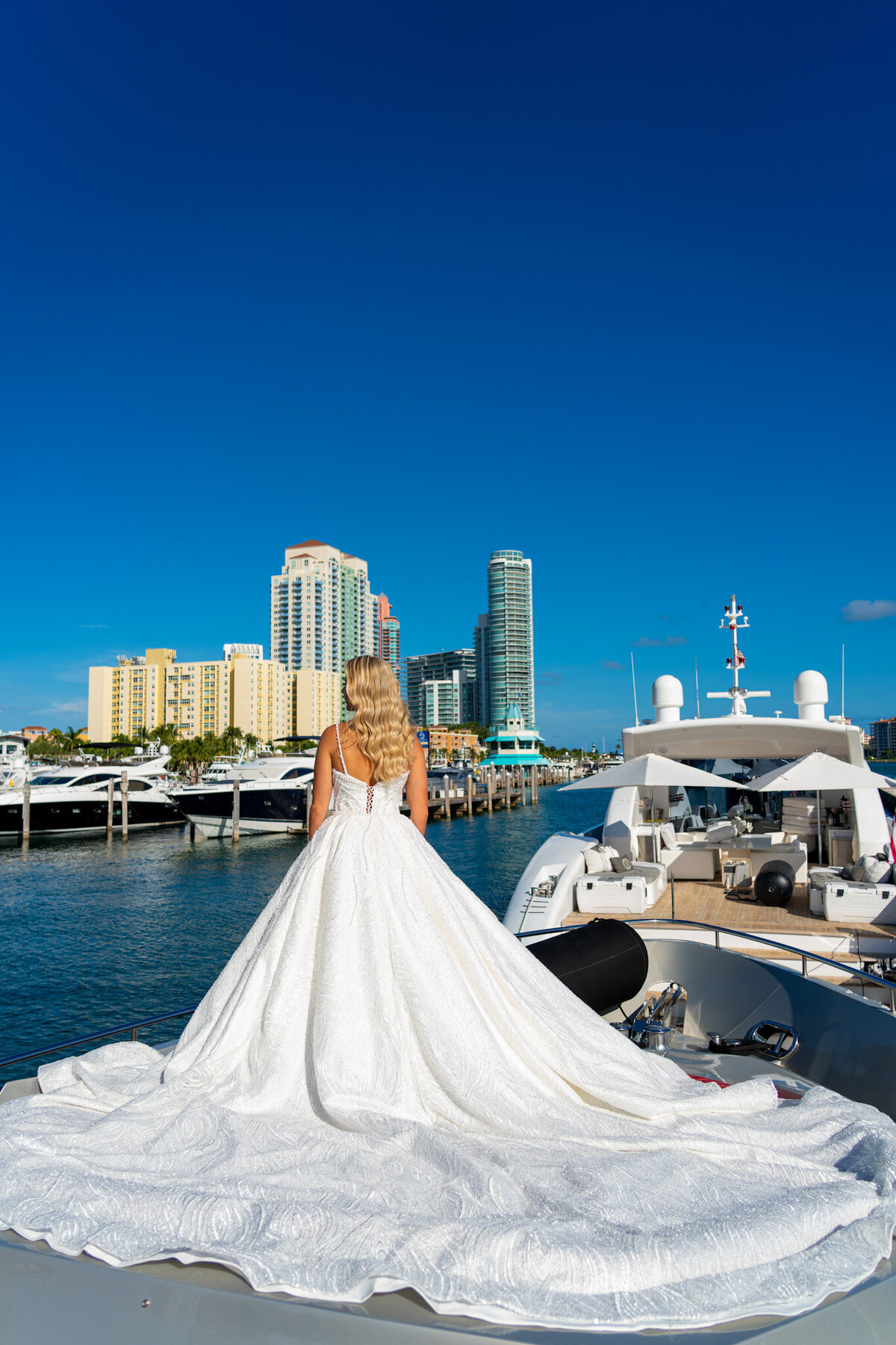 Bride models her pearl-detailed fit and flare wedding dress aboard luxury yacht.