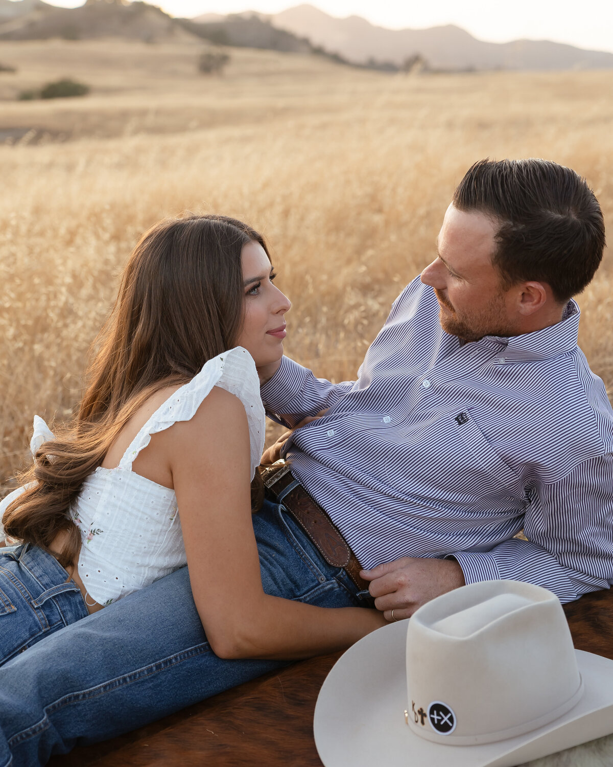 candid couples engagement photos in open field during golden hours in San Luis Obispo