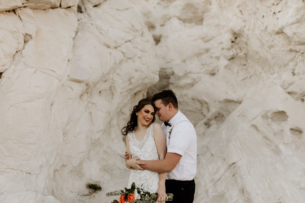 Bride and groom standing in front of a New Mexico white rock