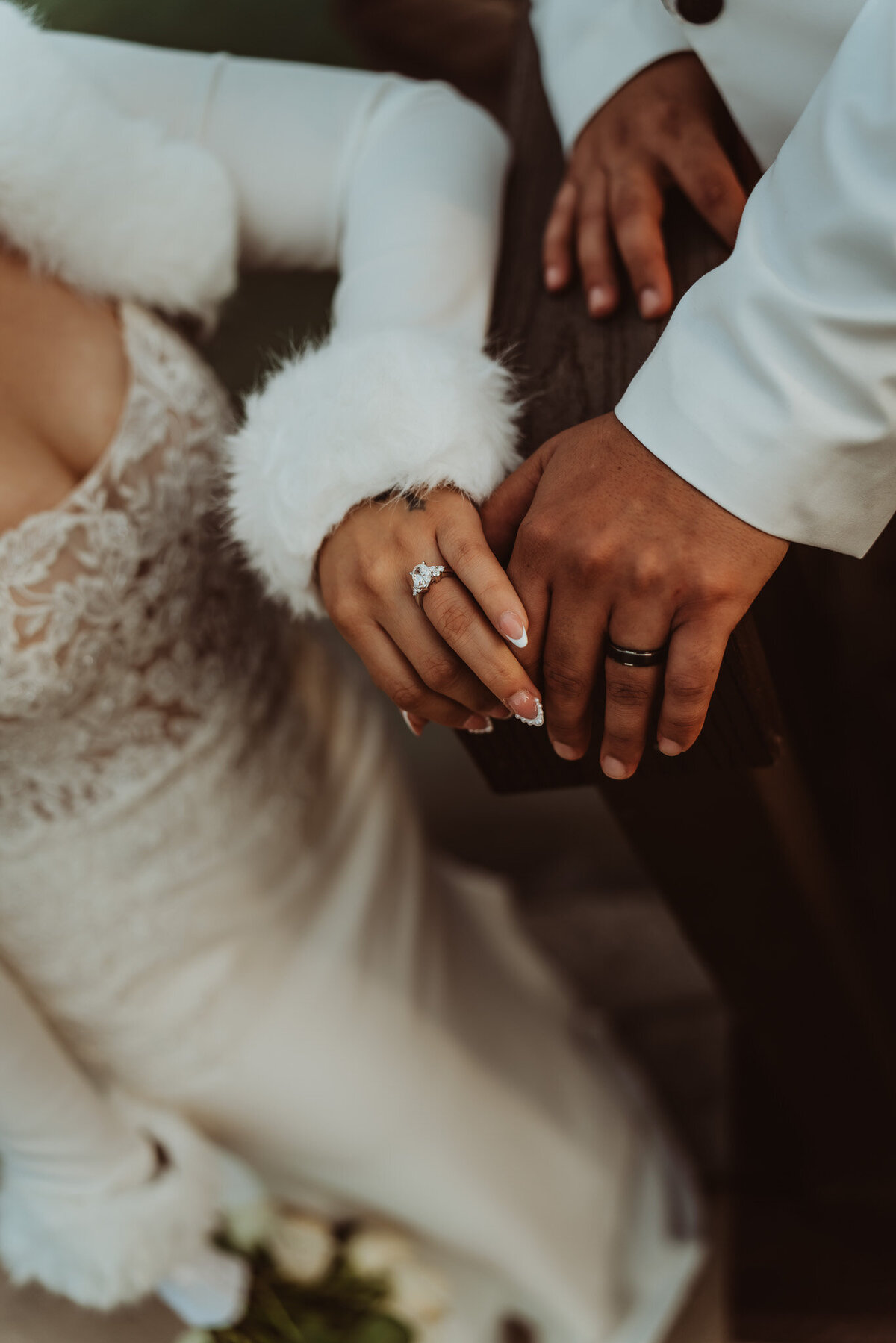 close up of newly weds hands resting on a fence showing rings 