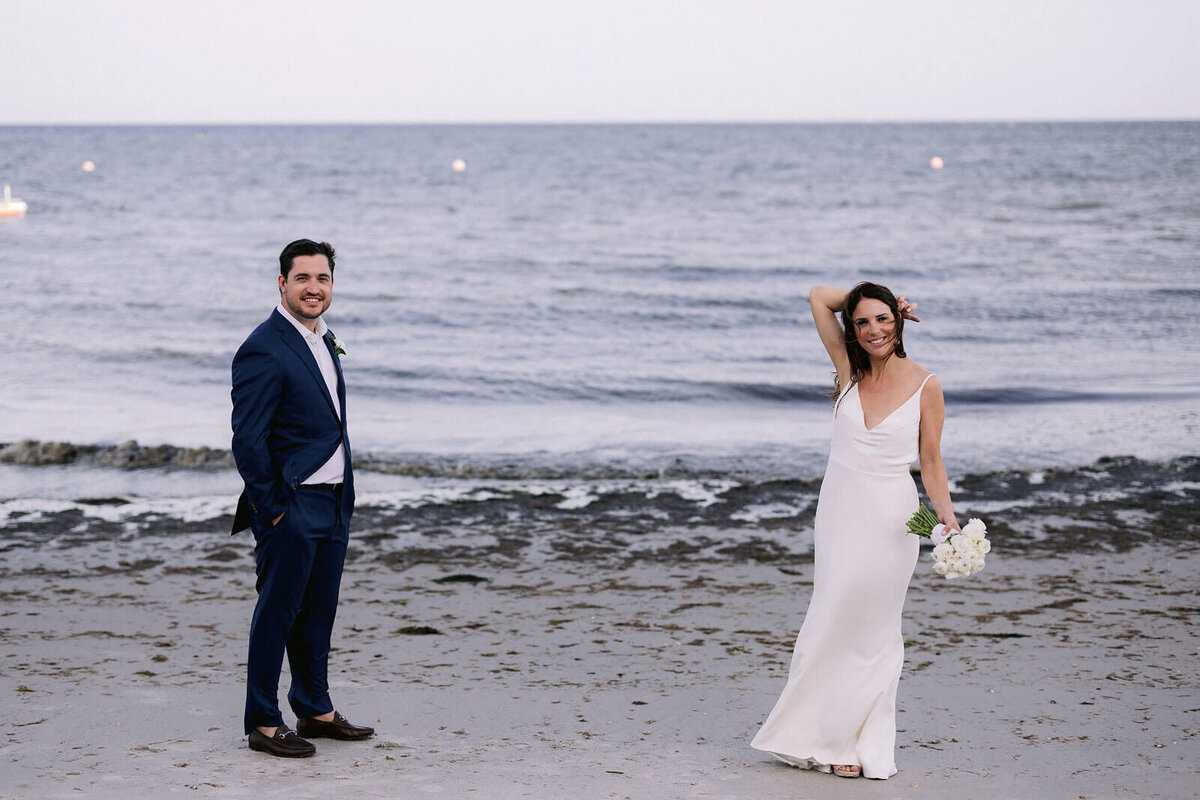 The bride and the groom are standing on a seashore in Cape Cod, MA.