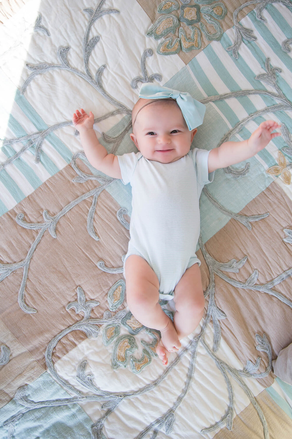 happy and excited baby girl in blue on a bed