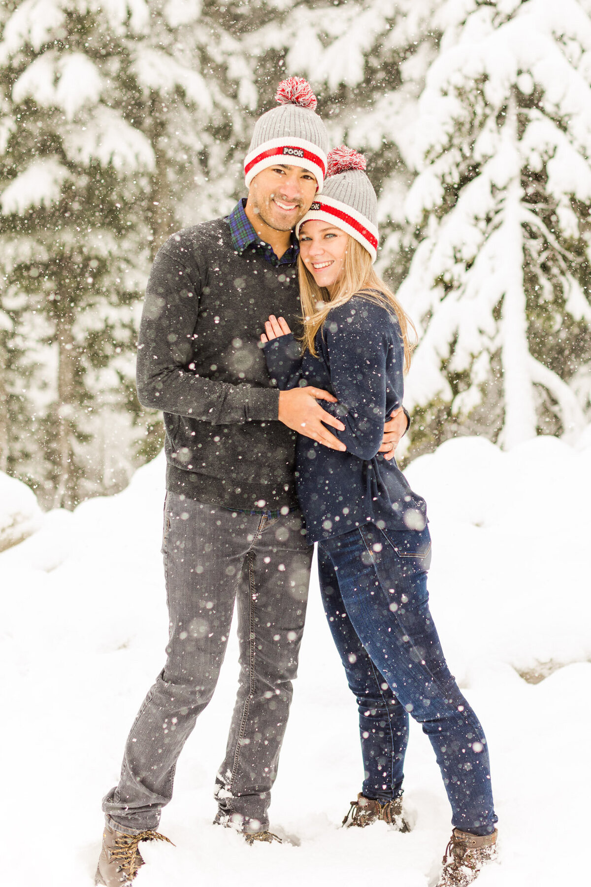 Beautiful couple at engagement session in the snow at Snoqualmie Pass wearing matching beanies near Seattle WA photo by Joanna Monger Photography