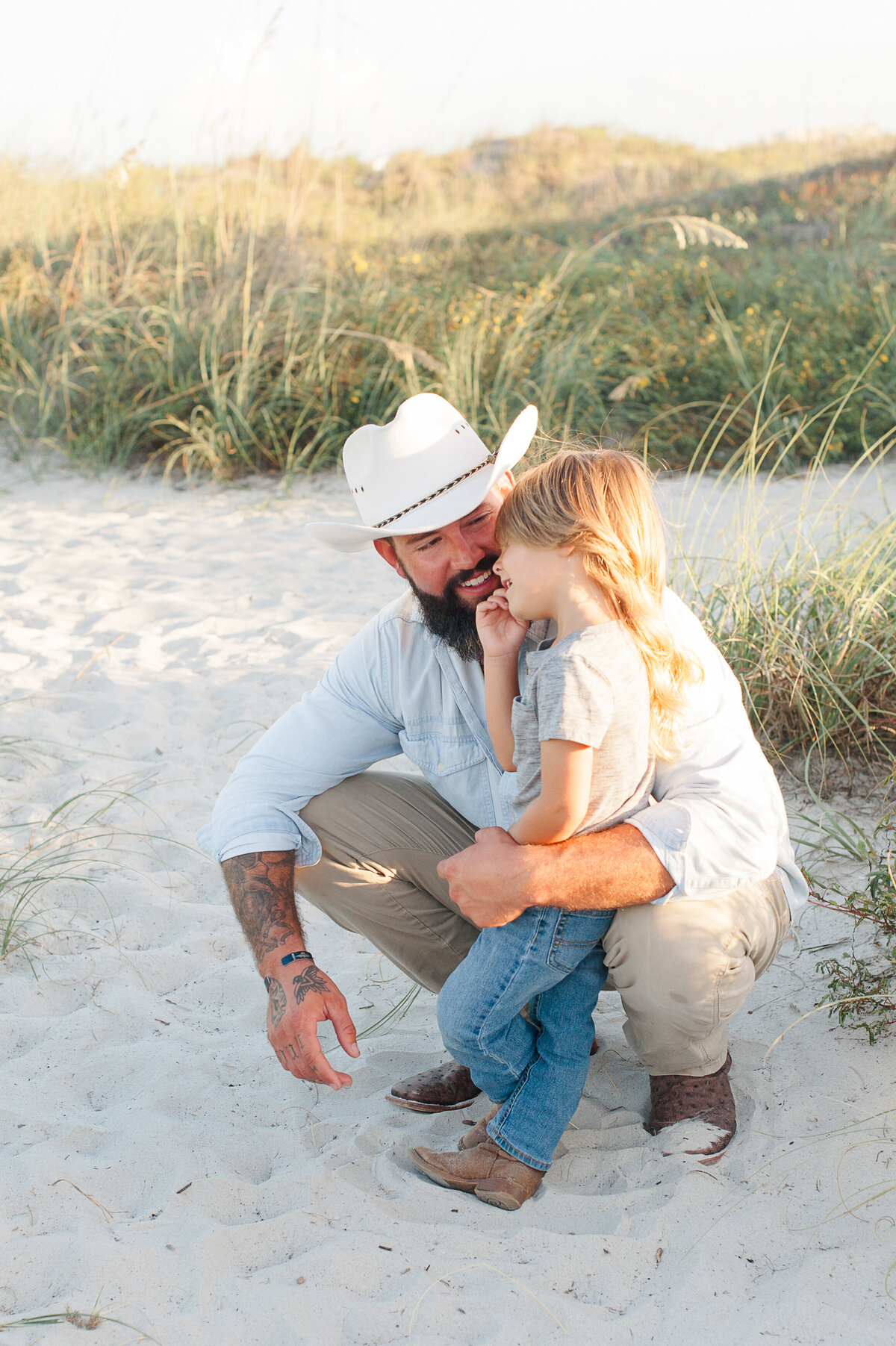 Dad laughing with son while standing near the dunes at golden hour