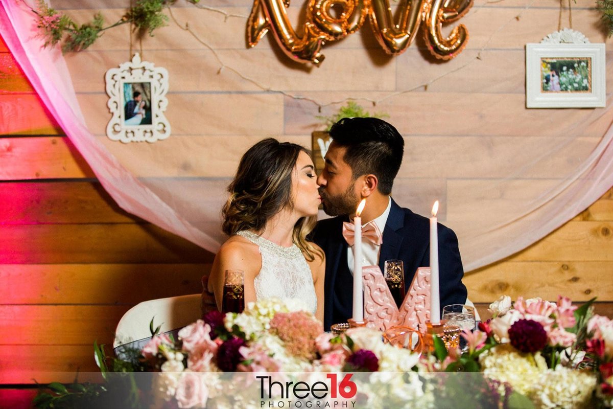 Bride and Groom share a kiss at the couple's dinner table