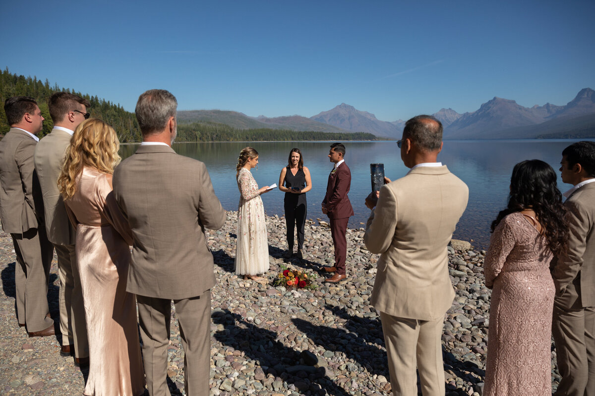 The bride reads her vows to her groom during their elopement ceremony as their family stands in a semi-circle around them.