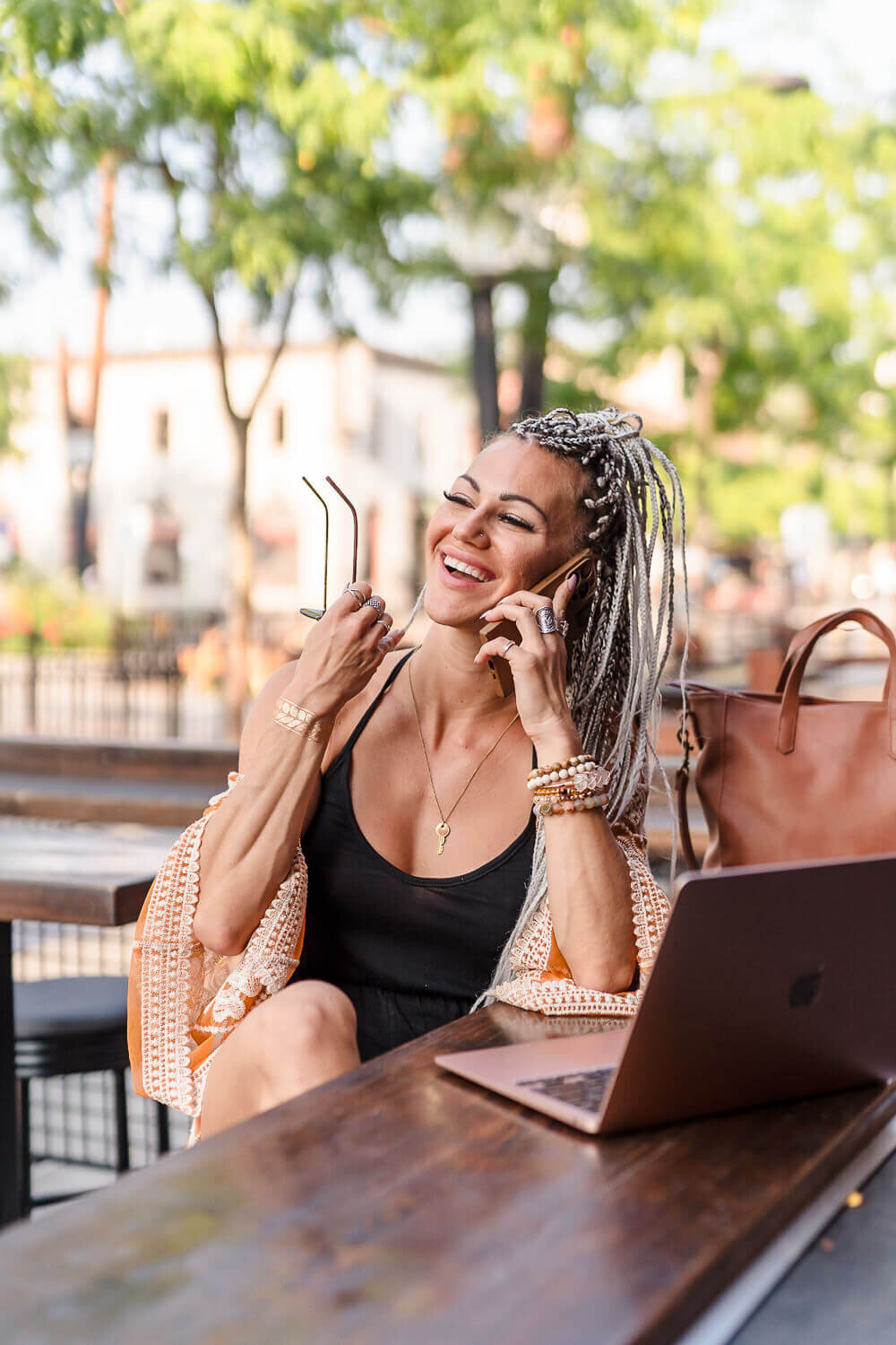 laughing woman on phone with braided hair on outdoor patio downtown Kelowna