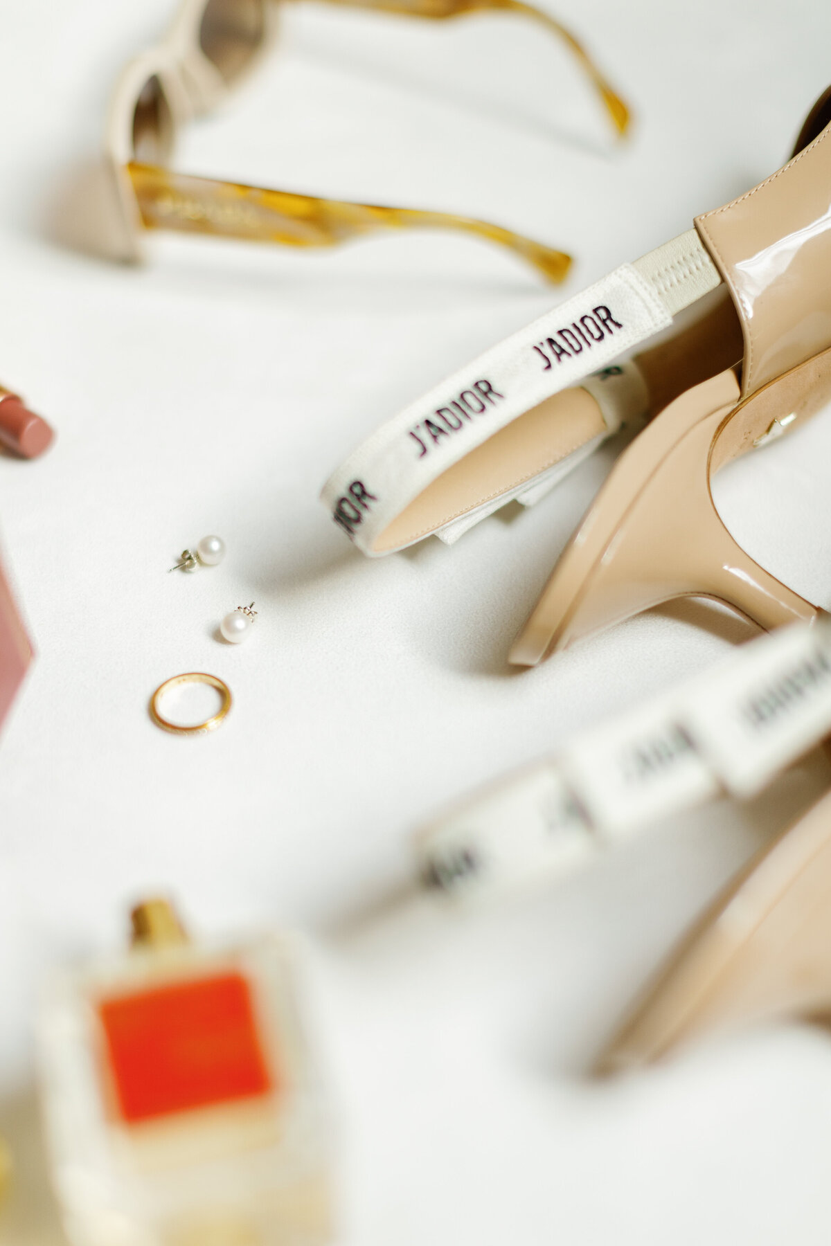 Close-up shot of wedding accessories including Dior shoes, pearl earrings, and perfume captured by Claudia Amalia Photography in Miami, Florida.