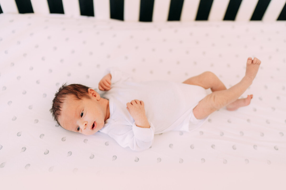 baby boy lays on hedgehog sheet wearing white onesie