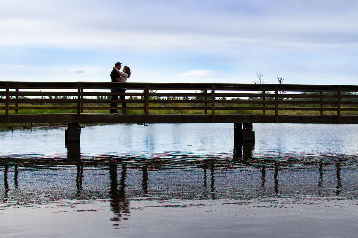 engaged couple kissing on the bridge