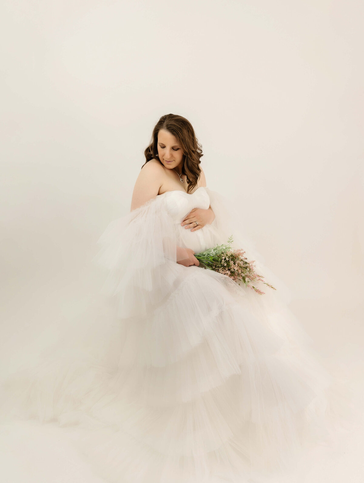 Maternity photo of a young woman wearing a full white dress in an Erie Pa photography studio