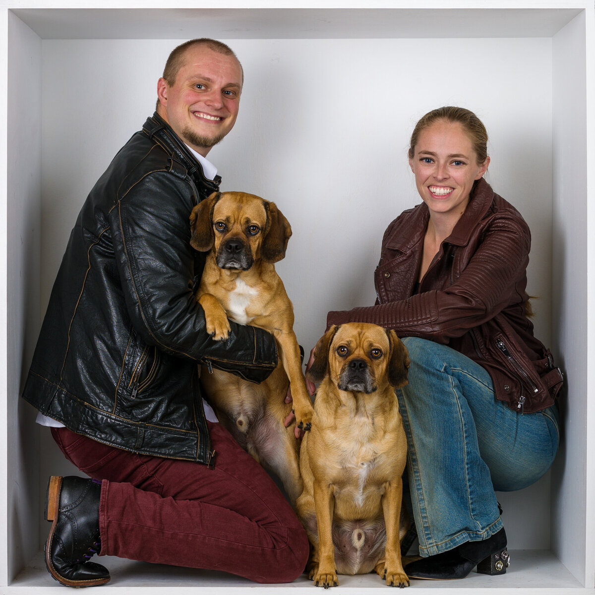 Headshot and branding photographer Jen & Travis from Fox & Brazen in  a white box holding dogs