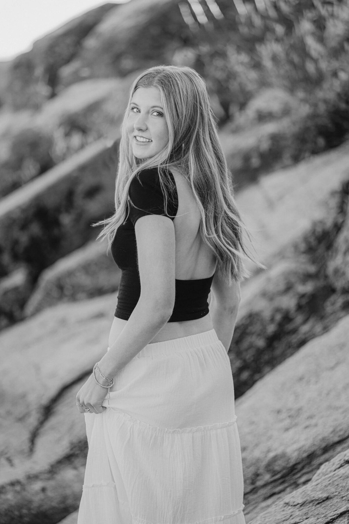 Black and white image of Senior girl walking through boulders at beach in Lake Tahoe