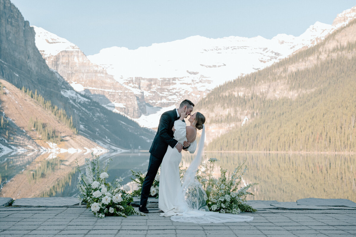 Couple kissing on wooden deck surrounded by mountain lake scenery