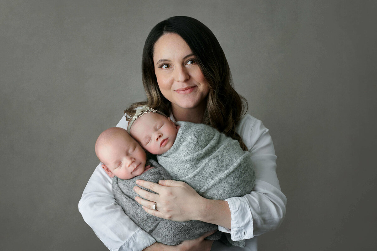 new mom holding her newborn twins at a newborn photoshoot