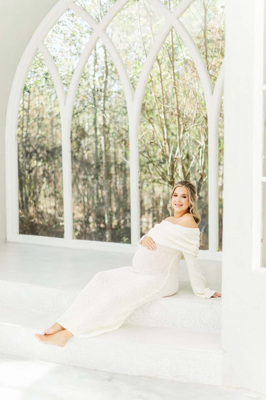 mom sits on the stairs of a houston studio holding pregnant belly