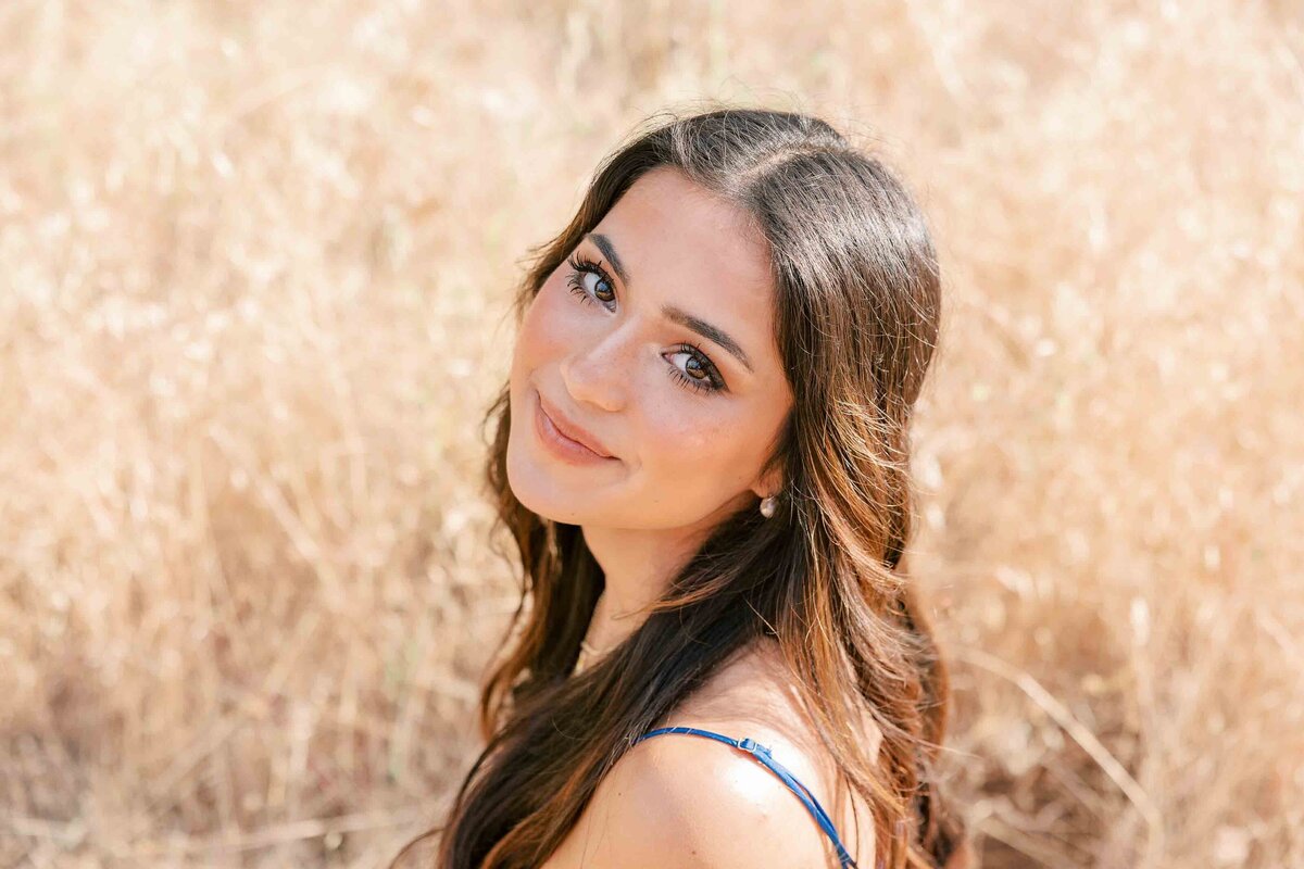 Brunette girl wearing a royal blue dress and looking up at the camera with a soft smile